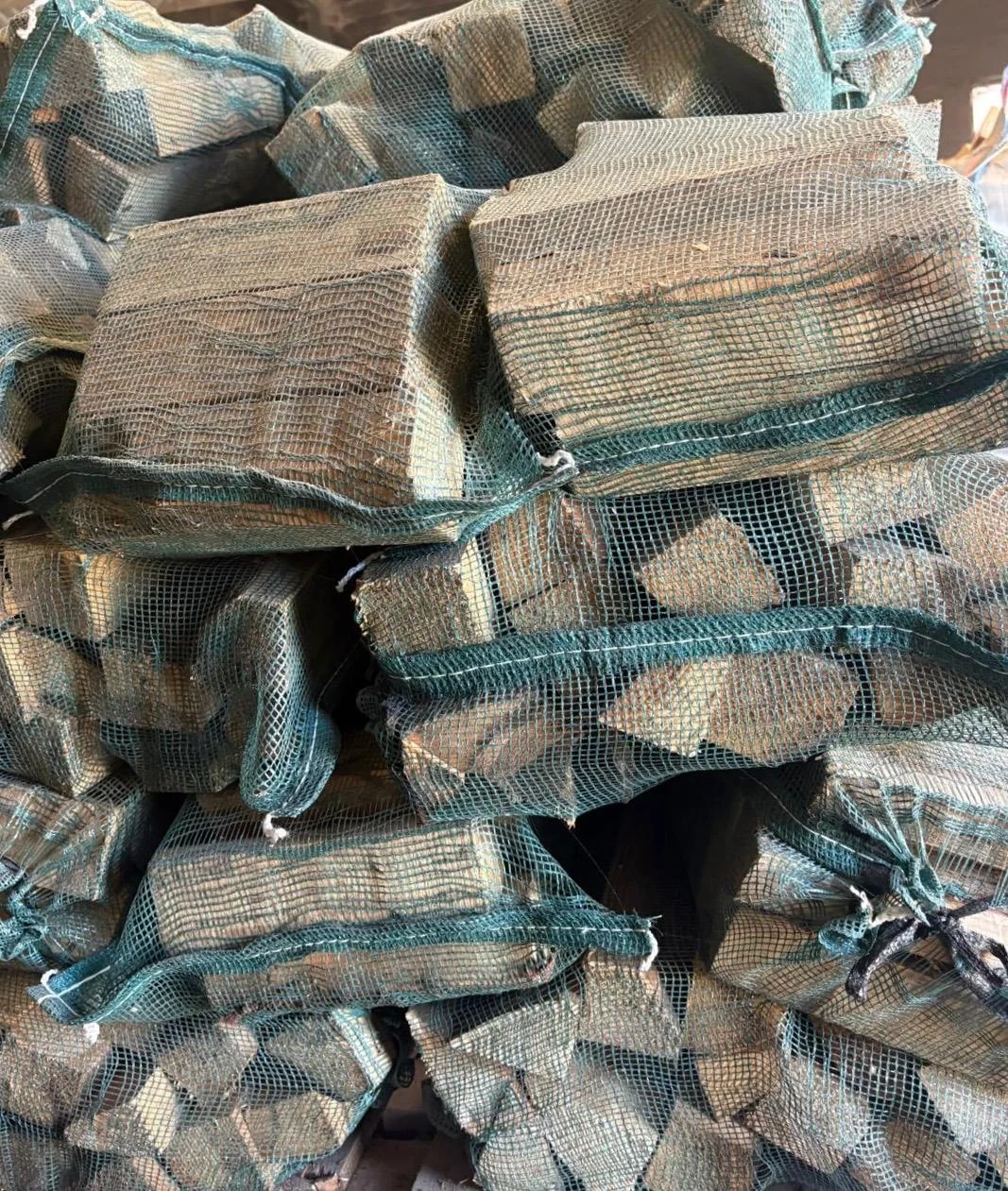 Square-cut logs packed in green mesh nets