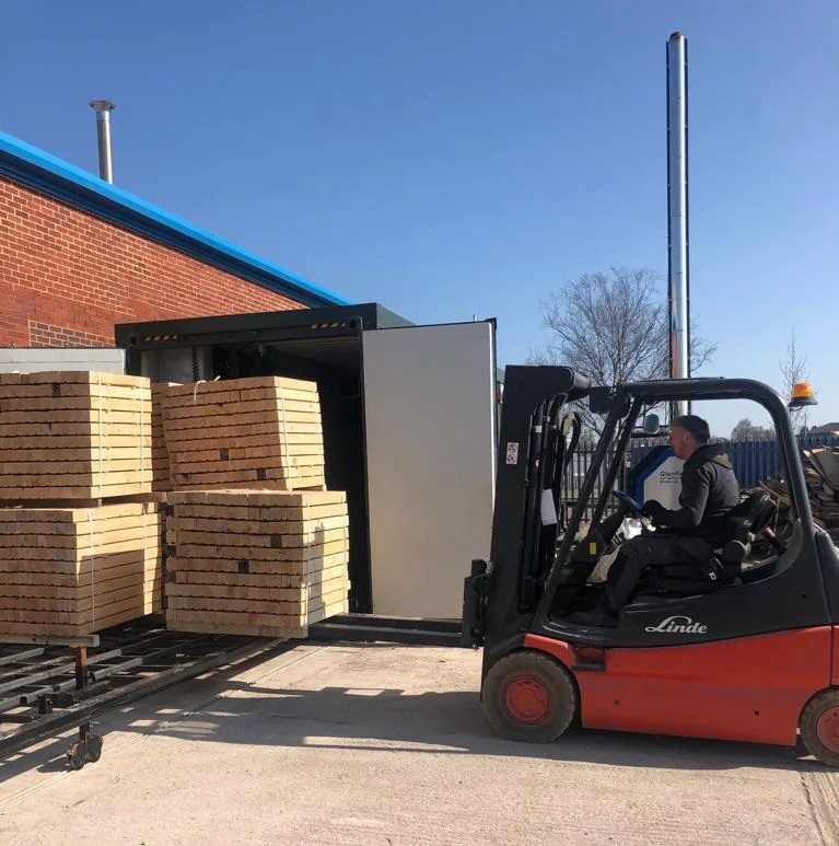 Forklift loading stacked timber into the kiln